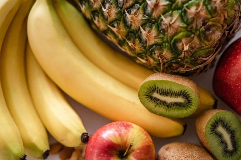 Fatias frescas de abacaxi e kiwi sobre tábua de madeira clara