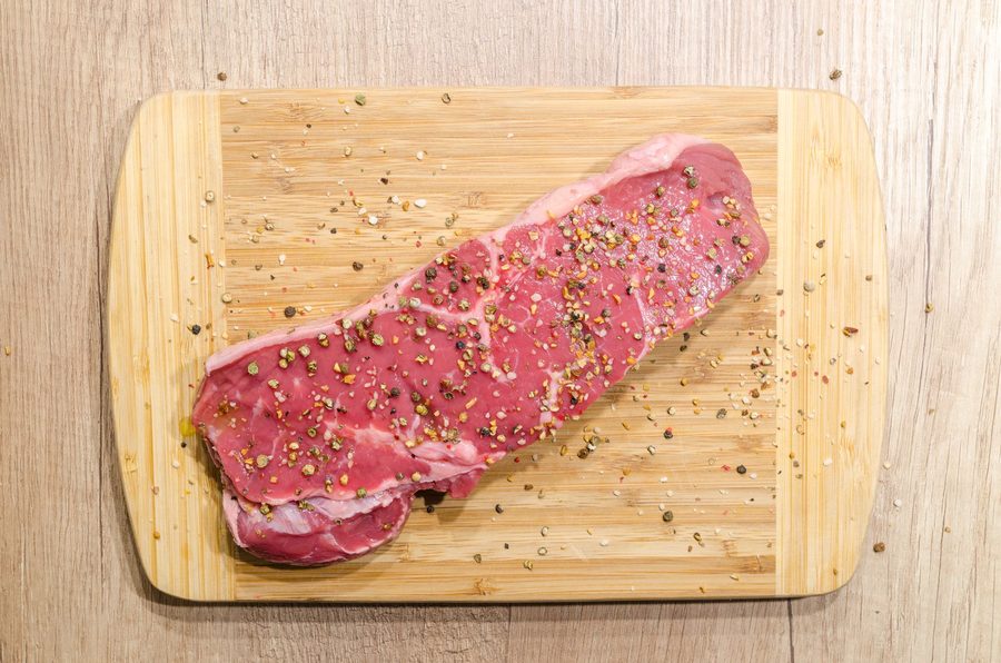Bife na grelha sendo testado com o dedo para checar o ponto